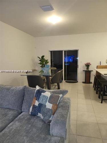 living area featuring light tile patterned flooring and visible vents