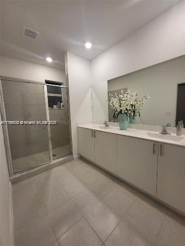 bathroom with a sink, tile patterned flooring, double vanity, recessed lighting, and a stall shower