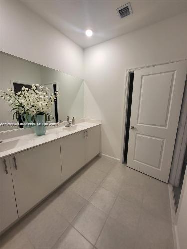 full bathroom with visible vents, double vanity, a sink, and tile patterned floors