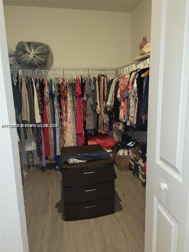 walk in closet with wood finished floors