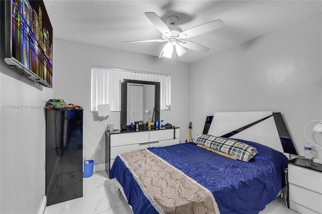 5061 W 12th Ln Unit E-10, Hialeah, FL 33012 - bedroom featuring a ceiling fan, a textured ceiling, baseboards, and marble finish floor