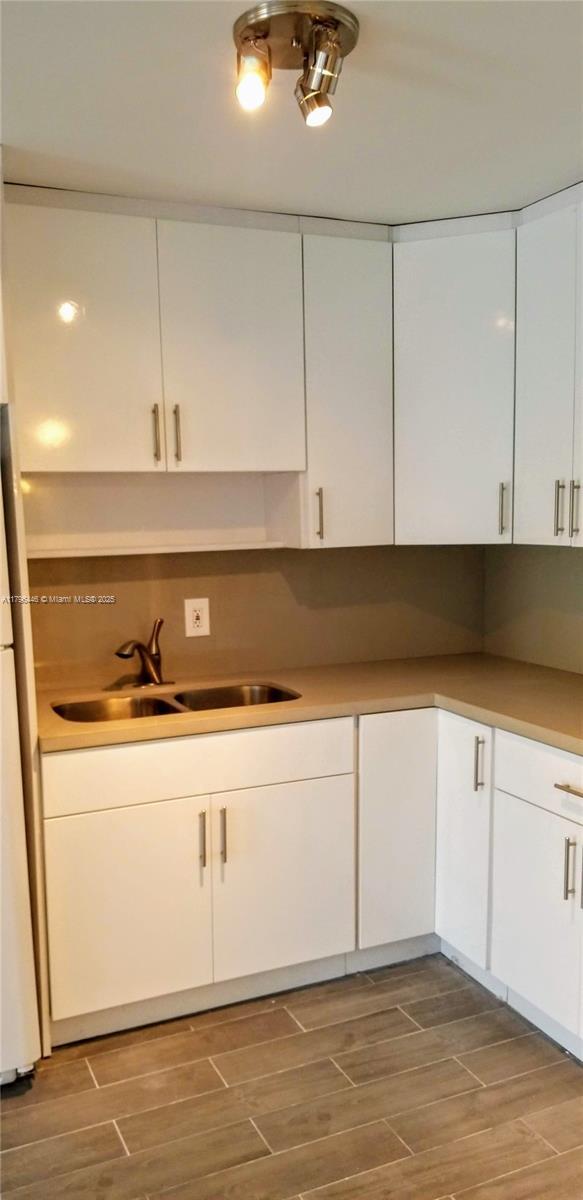 15205 NE 6th Ave Unit D204, Miami, FL 33162 - kitchen featuring white cabinets, wood finished floors, and a sink