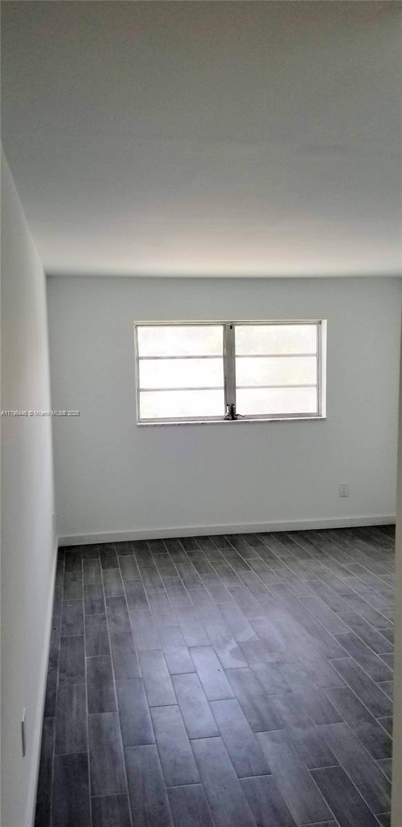 15205 NE 6th Ave Unit D204, Miami, FL 33162 - spare room featuring baseboards and dark wood-style floors