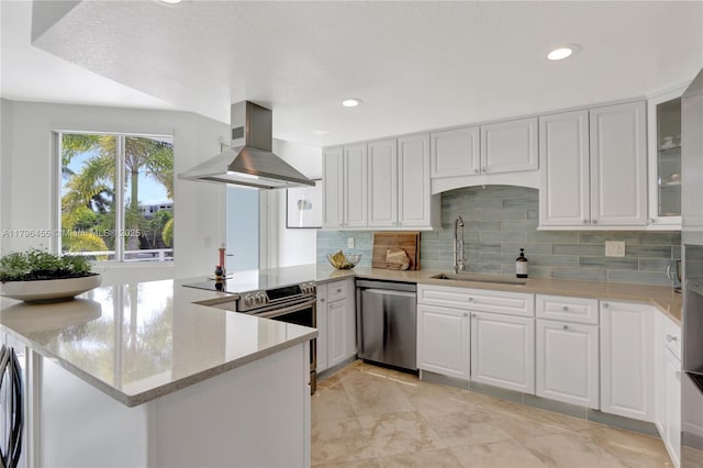 429 Hendricks Isle, Fort Lauderdale, FL 33301 - kitchen featuring stainless steel appliances, wall chimney range hood, a peninsula, a sink, and white cabinetry