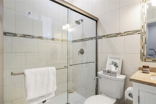 full bathroom with a stall shower, vanity, tile walls, and toilet