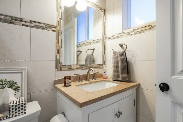 half bath featuring vanity, tile walls, toilet, and plenty of natural light