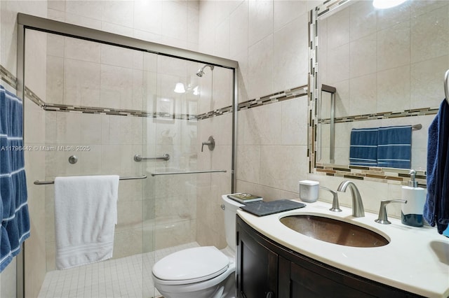 full bathroom featuring a stall shower, tile walls, vanity, and toilet