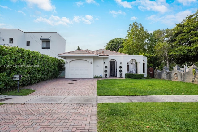 mediterranean / spanish-style house with a front lawn, stucco siding, an attached garage, and decorative driveway