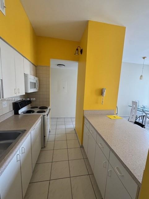 7400 W 20th Ave Unit 326, Hialeah, FL 33016 - kitchen with white appliances, white cabinets, light tile patterned flooring, light countertops, and backsplash