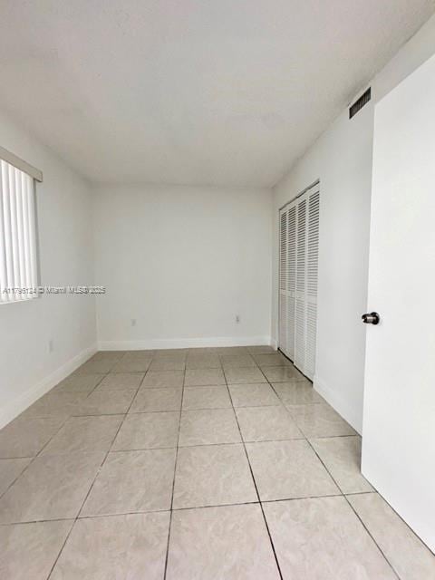 unfurnished room featuring light tile patterned flooring, baseboards, and visible vents