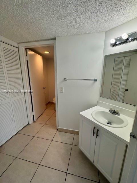 bathroom featuring a closet, a textured ceiling, toilet, tile patterned floors, and vanity