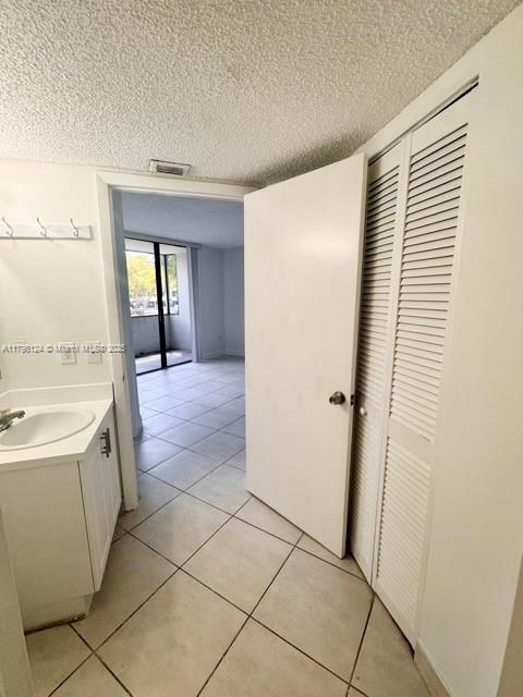 interior space featuring a textured ceiling, visible vents, tile patterned flooring, and vanity