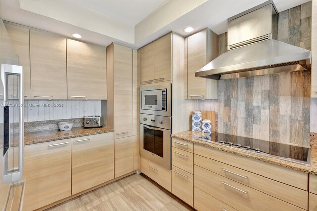 kitchen with tasteful backsplash, stainless steel appliances, light brown cabinets, and wall chimney exhaust hood