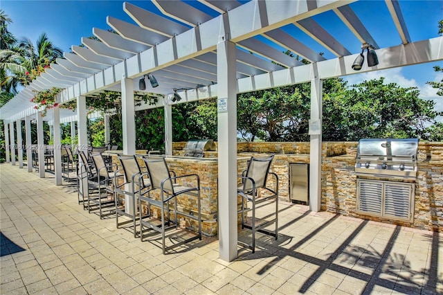 view of patio featuring a grill, a pergola, an outdoor kitchen, and outdoor wet bar