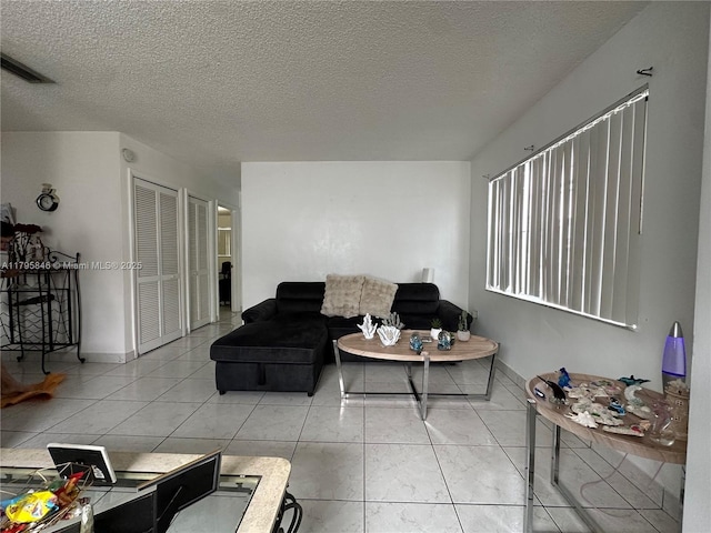 living area with a textured ceiling, baseboards, and visible vents