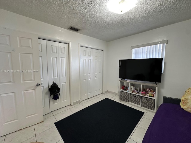living area featuring light tile patterned floors, visible vents, and a textured ceiling