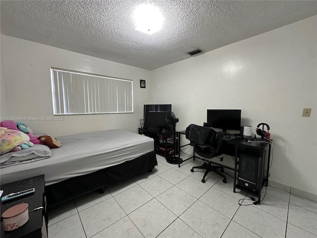 bedroom with a textured ceiling, light tile patterned flooring, and visible vents