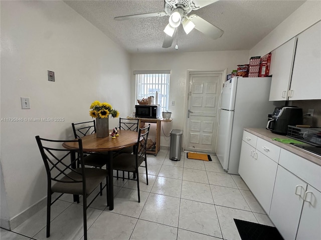 dining space with a ceiling fan, light tile patterned flooring, and a textured ceiling