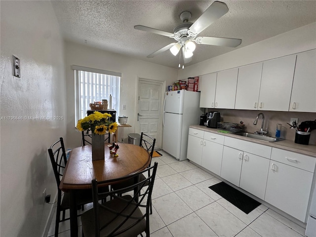 kitchen featuring a sink, freestanding refrigerator, a textured ceiling, and ceiling fan