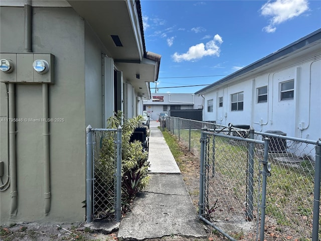 view of property exterior with central air condition unit, fence, stucco siding, and a gate