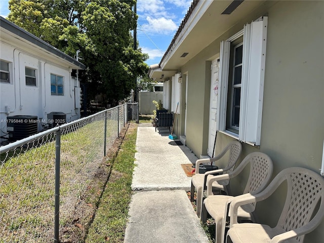 view of side of property with central air condition unit, stucco siding, and fence