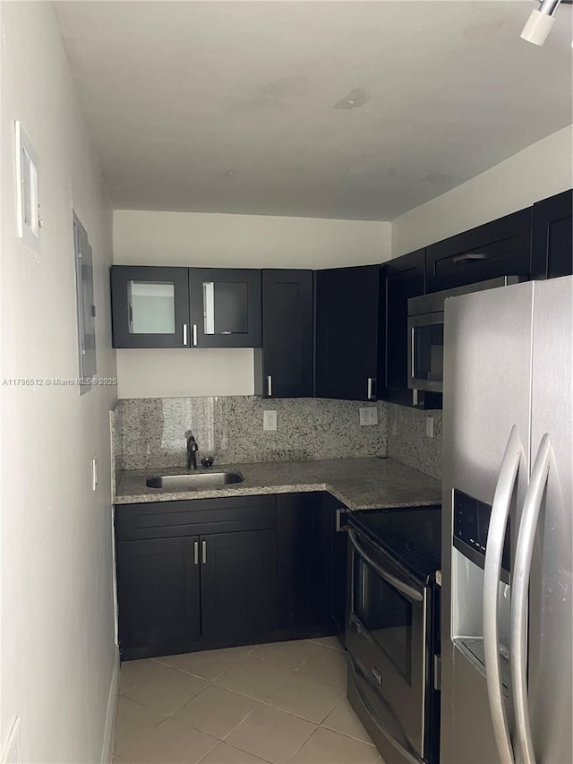 200 S Birch Rd Unit 1111, Fort Lauderdale, FL 33316 - kitchen featuring light tile patterned floors, a sink, backsplash, appliances with stainless steel finishes, and dark cabinetry