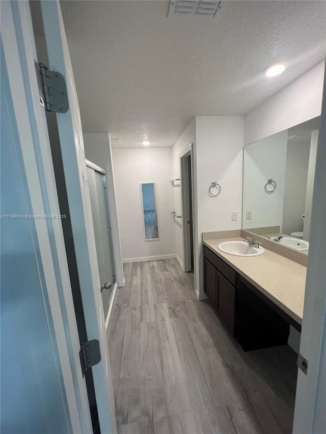 203 Palmwood Dr, Palm Coast, FL 32164 - bathroom featuring a stall shower, a textured ceiling, visible vents, vanity, and wood finished floors