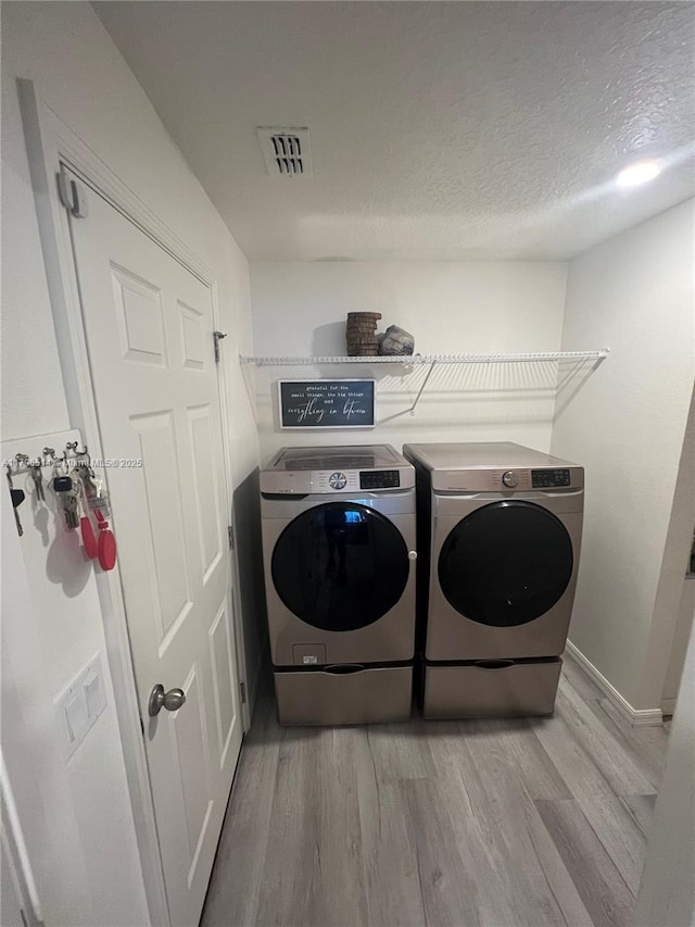 203 Palmwood Dr, Palm Coast, FL 32164 - clothes washing area featuring washing machine and clothes dryer, laundry area, visible vents, and light wood-style floors