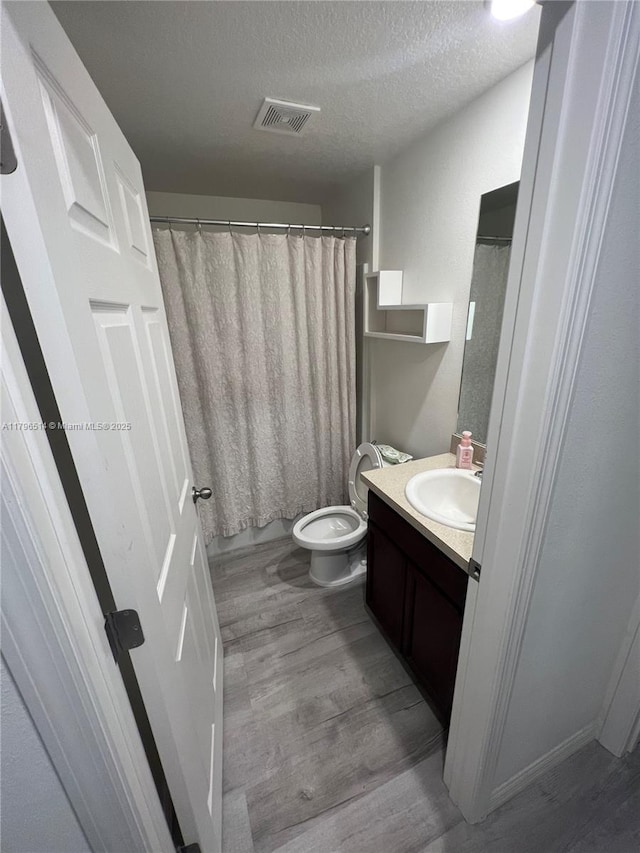 203 Palmwood Dr, Palm Coast, FL 32164 - full bath with toilet, wood finished floors, vanity, a textured ceiling, and visible vents