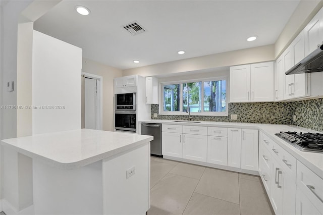1438 Harrison St, Hollywood, FL 33020 - kitchen with stainless steel appliances, backsplash, light countertops, white cabinetry, and light tile patterned flooring