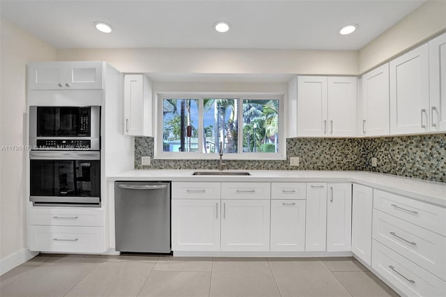 1438 Harrison St, Hollywood, FL 33020 - kitchen with stainless steel appliances, a sink, decorative backsplash, light countertops, and white cabinetry