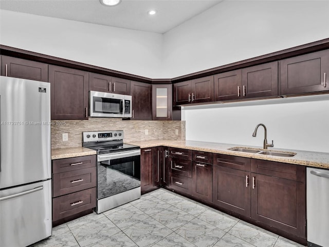 kitchen featuring dark brown cabinets, a sink, stainless steel appliances, backsplash, and marble finish floor