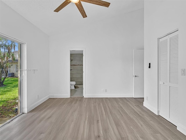 unfurnished bedroom featuring a ceiling fan, a closet, baseboards, ensuite bath, and wood finished floors