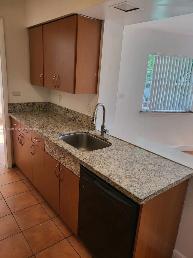 kitchen featuring light tile patterned floors, black dishwasher, and a sink
