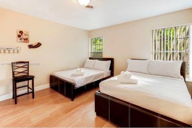 bedroom with visible vents, light wood-style flooring, and baseboards
