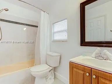 full bath with toilet, shower / bath combo with shower curtain, vanity, tile patterned flooring, and baseboards