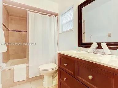 bathroom with toilet, tile patterned floors, vanity, and curtained shower