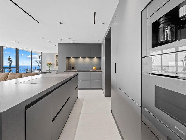 3101 S Ocean Dr Unit 2905, Hollywood, FL 33019 - kitchen with modern cabinets, gray cabinets, a water view, open floor plan, and light tile patterned floors