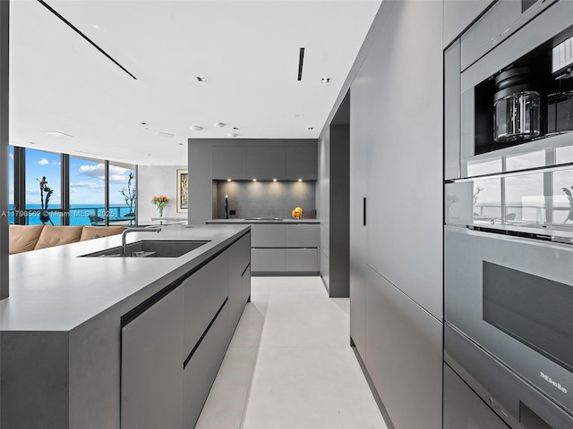 3101 S Ocean Dr Unit 2905, Hollywood, FL 33019 - kitchen with modern cabinets, a sink, stainless steel oven, gray cabinets, and a kitchen island with sink