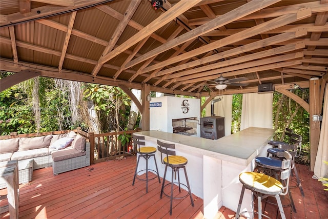wooden terrace featuring ceiling fan, outdoor lounge area, a gazebo, and outdoor wet bar