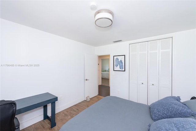 bedroom featuring a closet, visible vents, wood finished floors, and baseboards