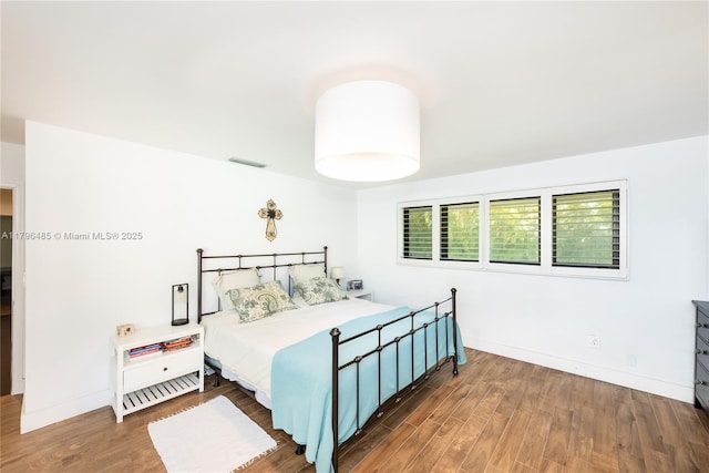 bedroom with visible vents, wood finished floors, and baseboards