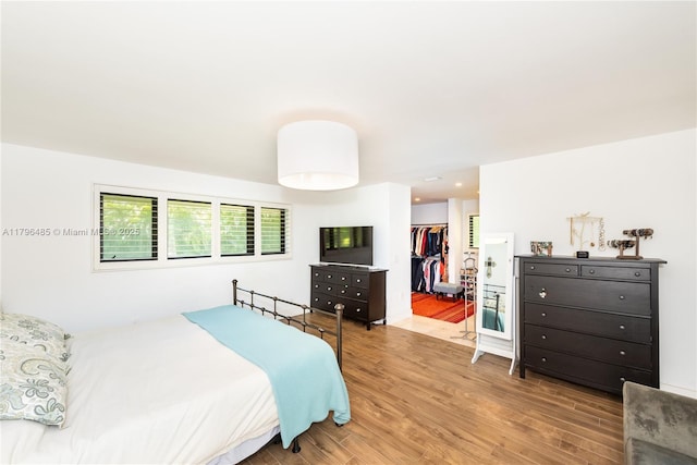 bedroom featuring a spacious closet, a closet, and wood finished floors