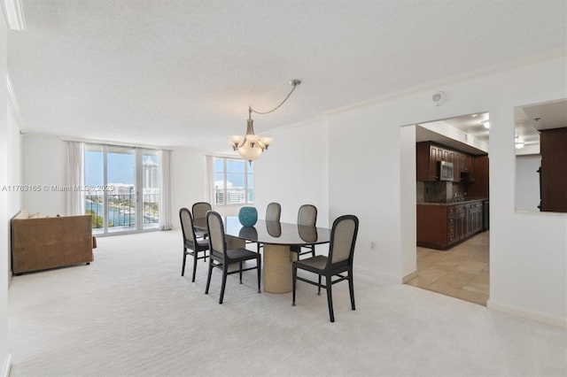 dining room with light colored carpet, crown molding, baseboards, and a notable chandelier