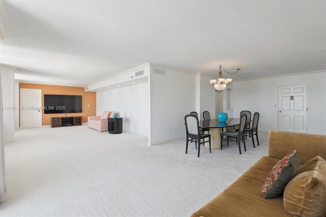 living room featuring a textured ceiling, carpet flooring, a notable chandelier, and visible vents
