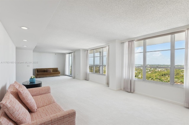 living area with a textured ceiling, carpet, baseboards, and recessed lighting