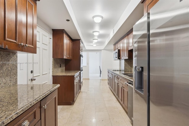 kitchen with stone countertops, appliances with stainless steel finishes, decorative backsplash, and baseboards