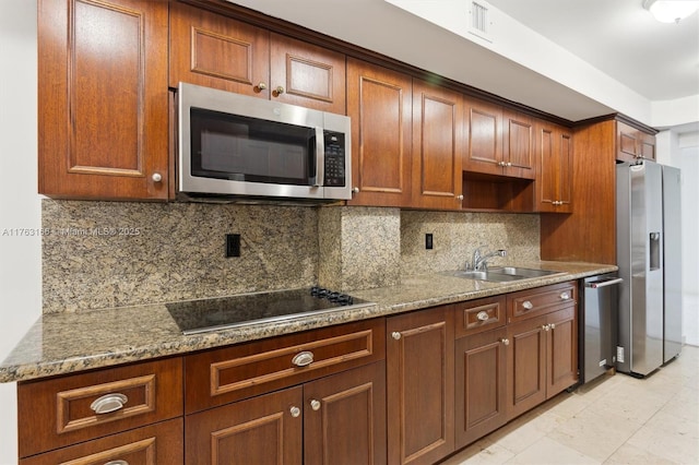 kitchen featuring backsplash, appliances with stainless steel finishes, light stone countertops, and a sink