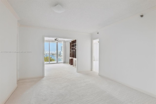 spare room featuring crown molding, light carpet, and ceiling fan