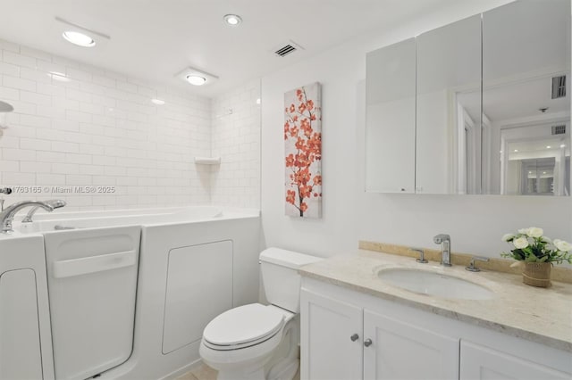 bathroom featuring toilet, vanity, visible vents, recessed lighting, and a washtub